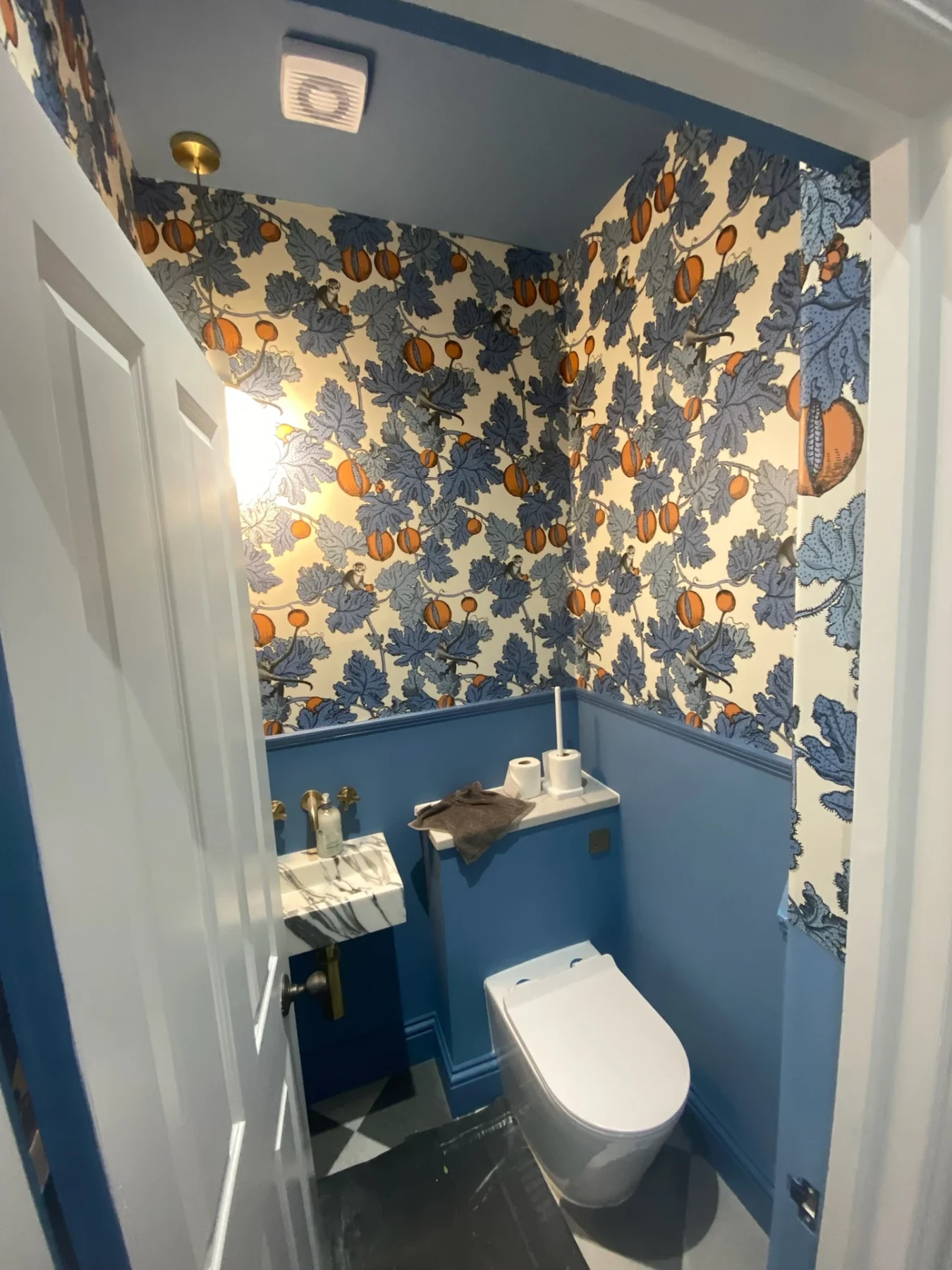 Small bathroom with blue vanity and patterned wallpaper