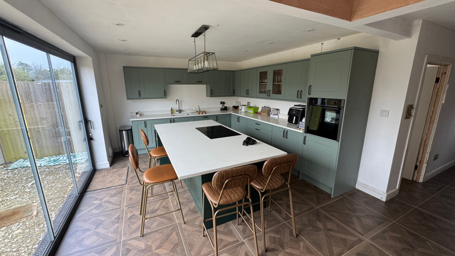 Kitchen renovation with an island, green cabinetry and herringbone flooring