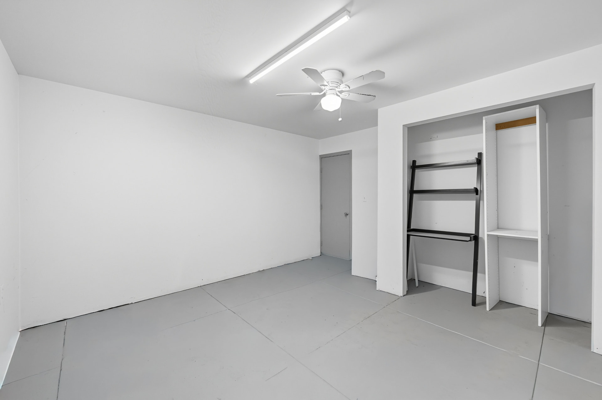 White-painted room with grey floor, ceiling fan and built-in storage shelving
