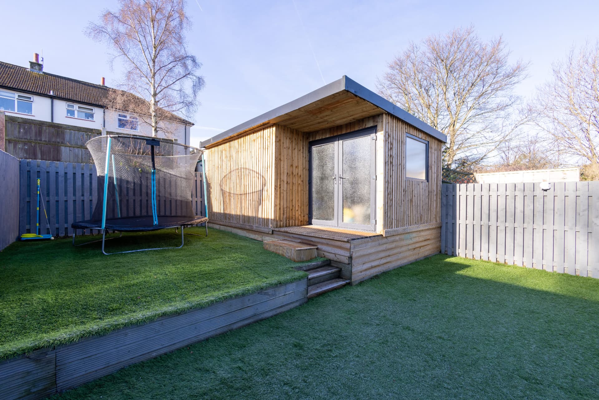 Timber-clad garden room with glazed double doors, side window and stepped decking