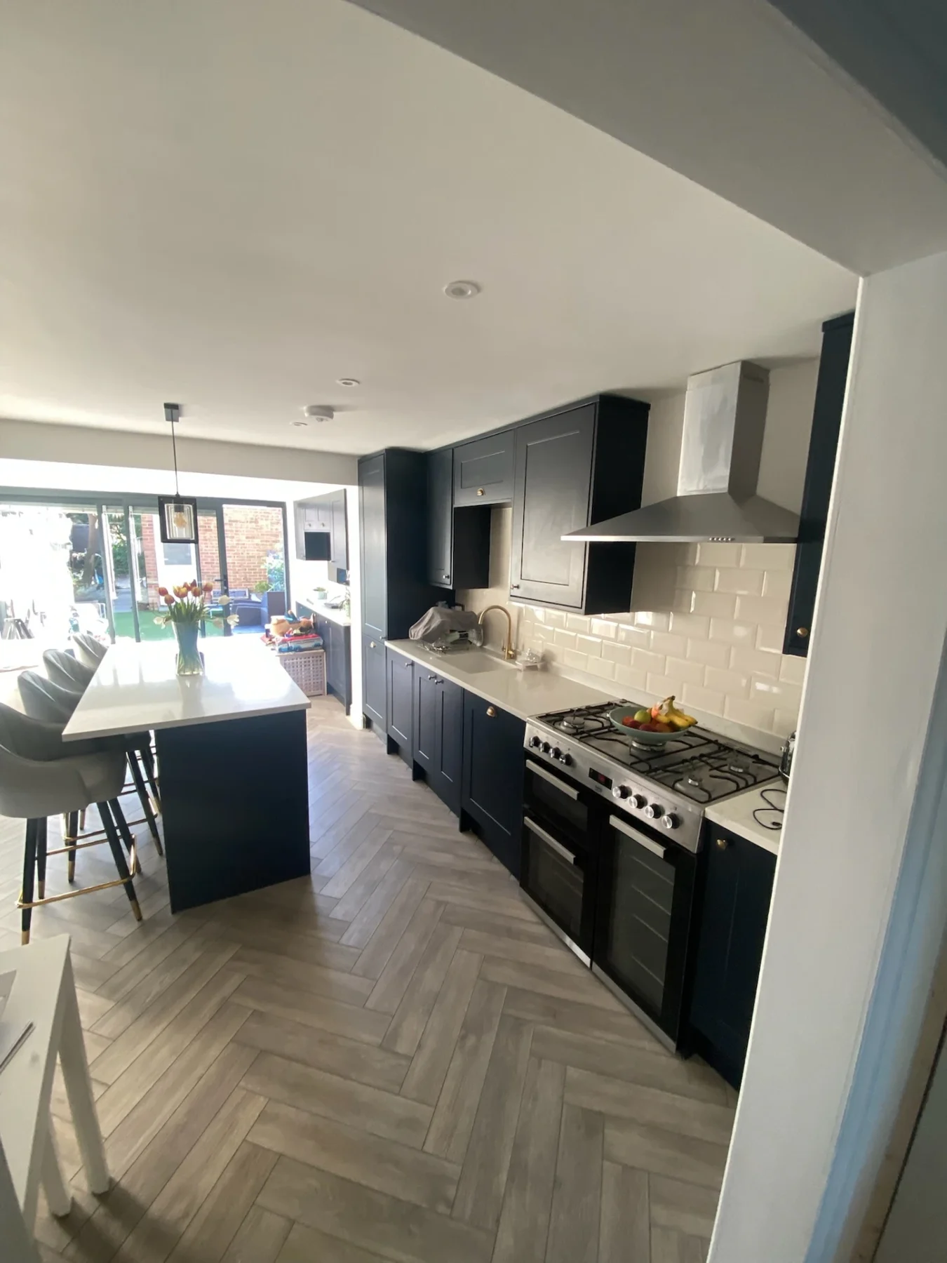 Navy kitchen with island and herringbone floor opening onto the garden