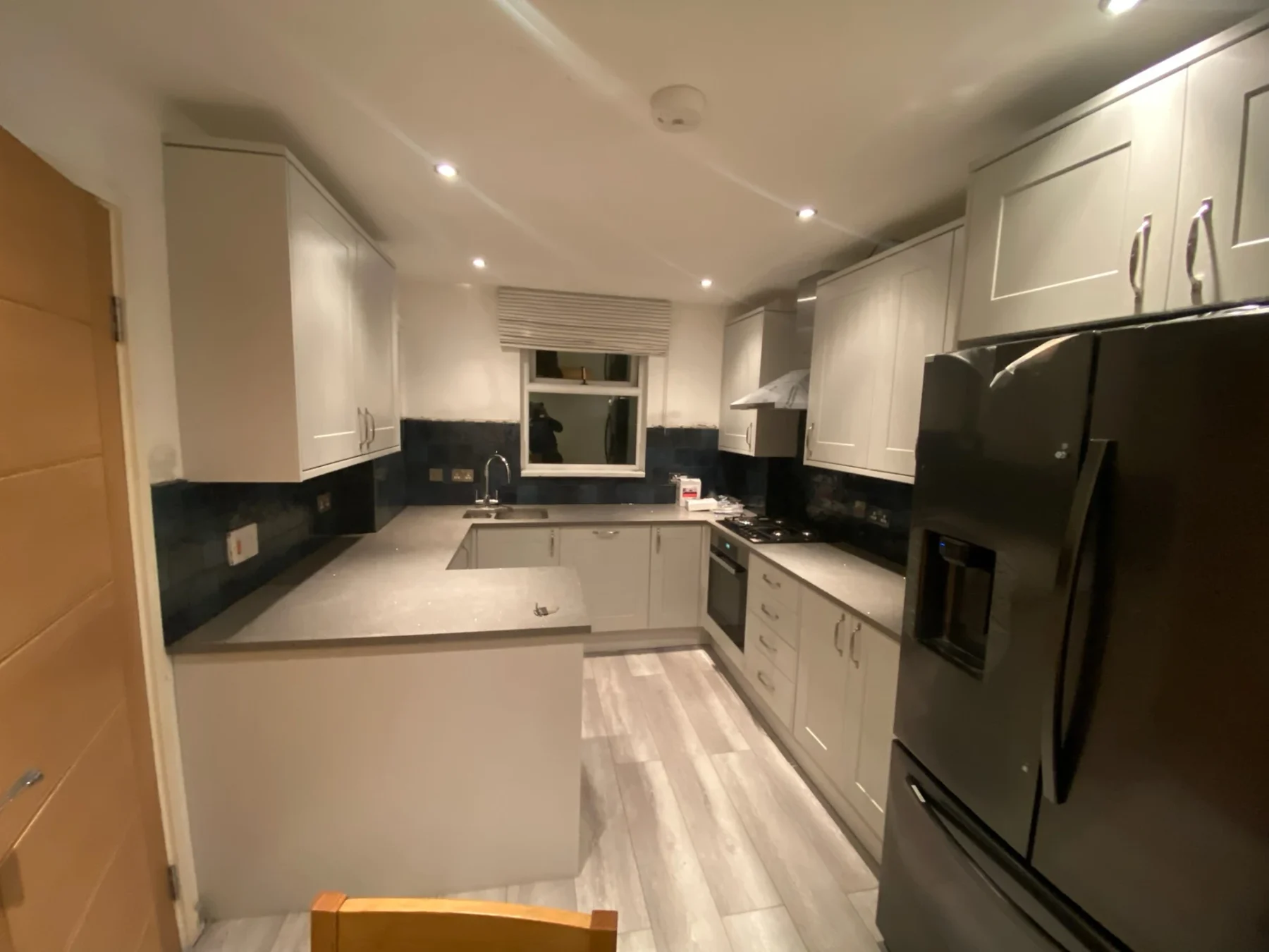 White kitchen with dark worktops and a black tiled splashback