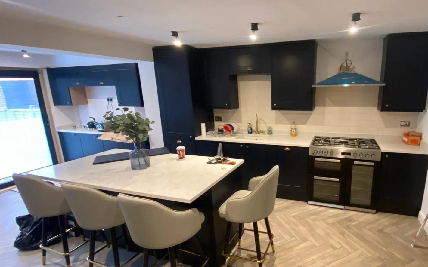 Navy shaker kitchen with marble-effect island, bar stools and herringbone floor