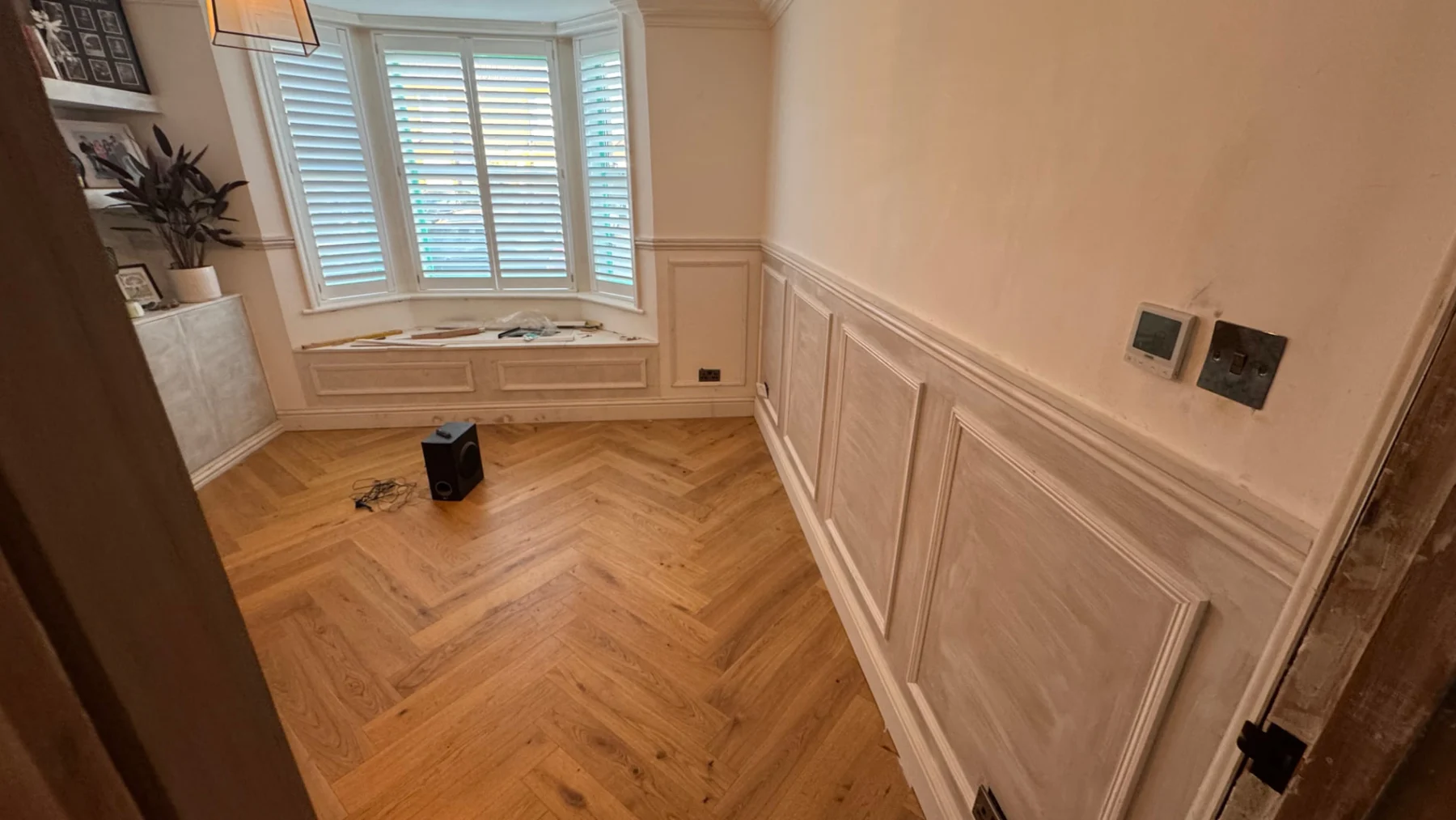 Renovated room with decorative wall panelling and oak herringbone flooring