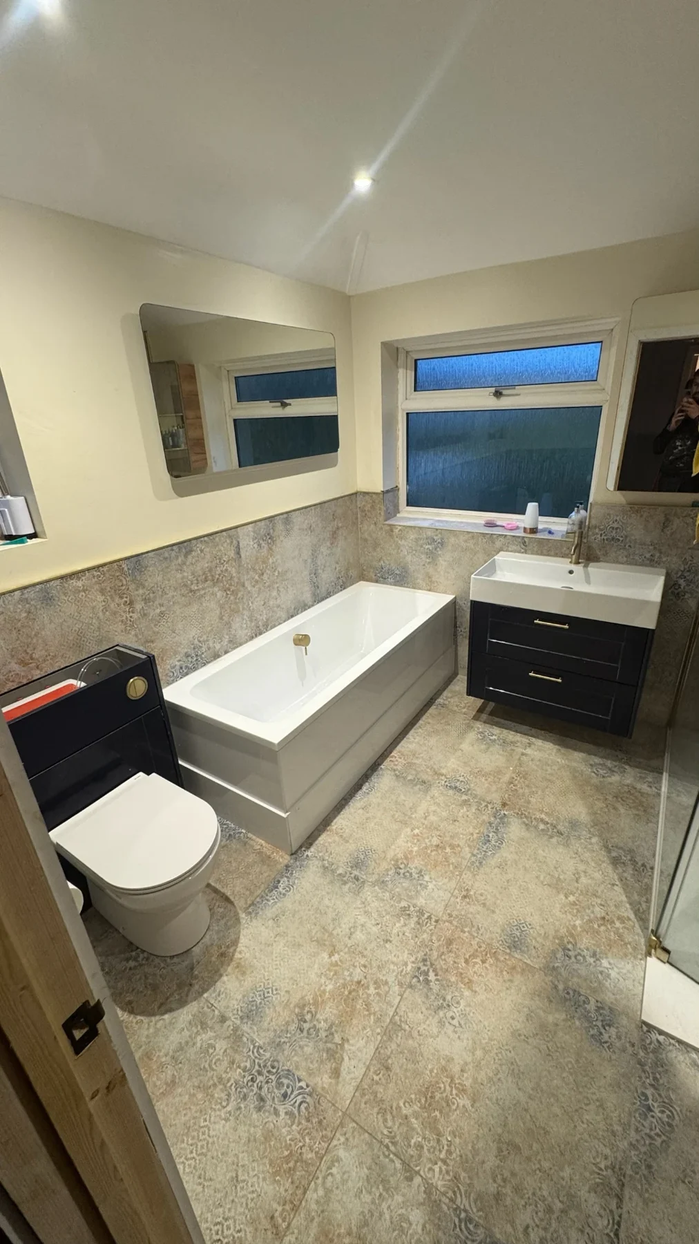 Compact bathroom with dark vanity and stone-effect tiled floor